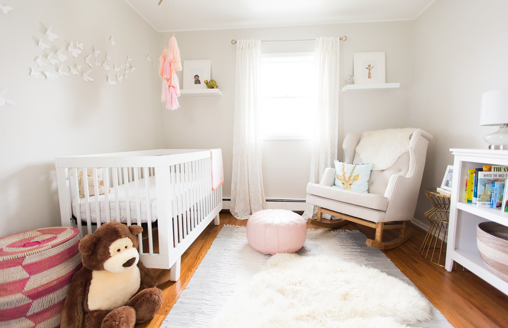 Modelo de habitación de bebé niña clásica renovada de tamaño medio con suelo de madera en tonos medios