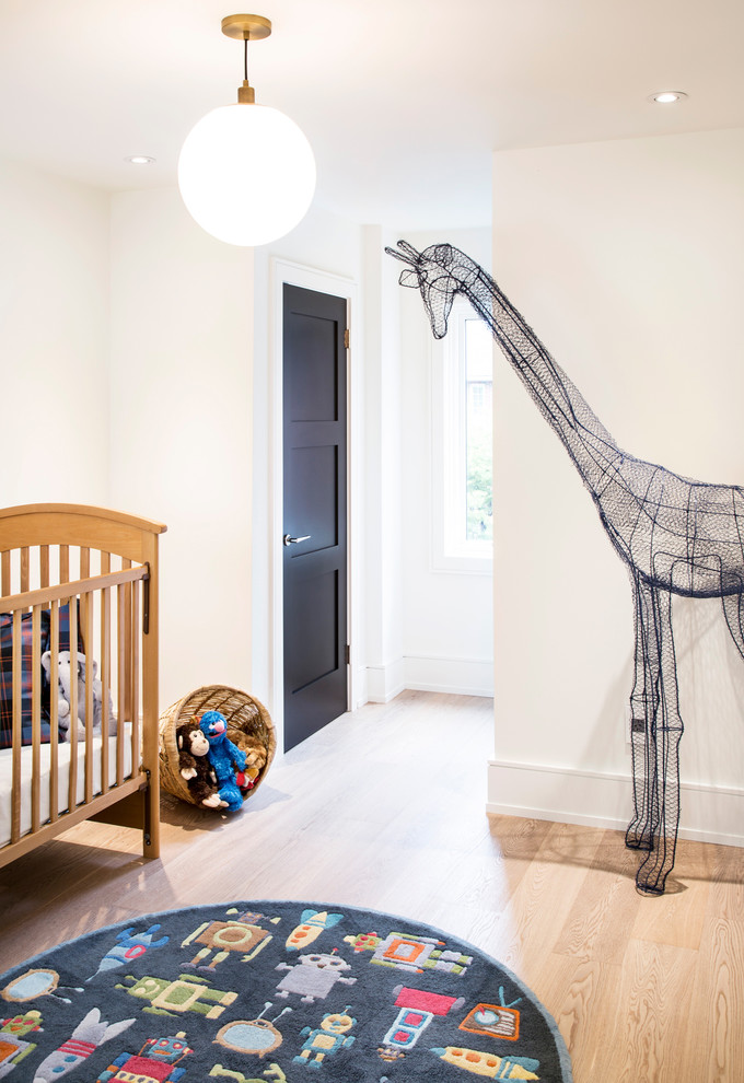 Cette photo montre une chambre de bébé neutre chic de taille moyenne avec un mur blanc, parquet clair et un sol marron.