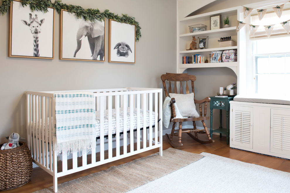 Modelo de habitación de bebé neutra clásica renovada con paredes grises y suelo de madera en tonos medios