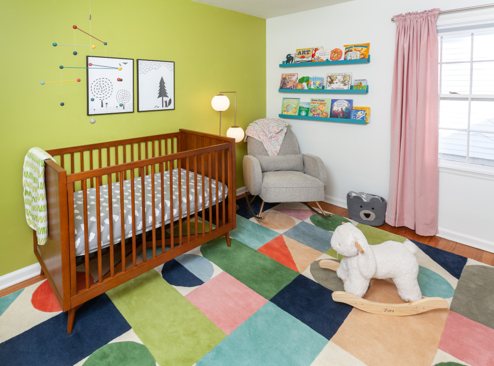 Idée de décoration pour une petite chambre de bébé fille vintage avec un mur vert, un sol en bois brun et un sol multicolore.