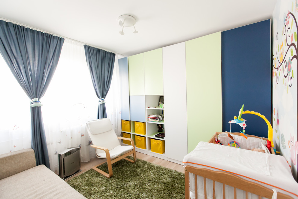 Inspiration for a small contemporary nursery for boys in Other with white walls and light hardwood flooring.