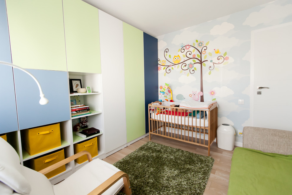 Small contemporary nursery for boys in Other with white walls and light hardwood flooring.