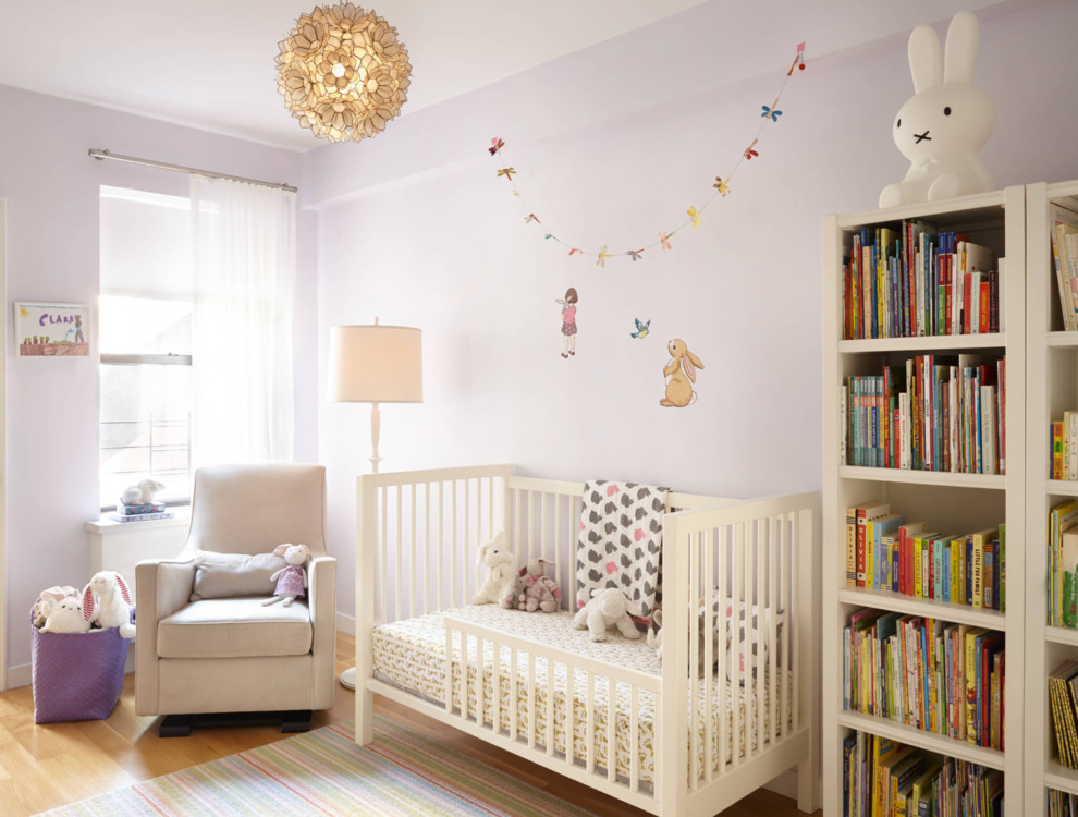Réalisation d'une chambre de bébé fille tradition de taille moyenne avec parquet clair, un mur violet et un sol marron.