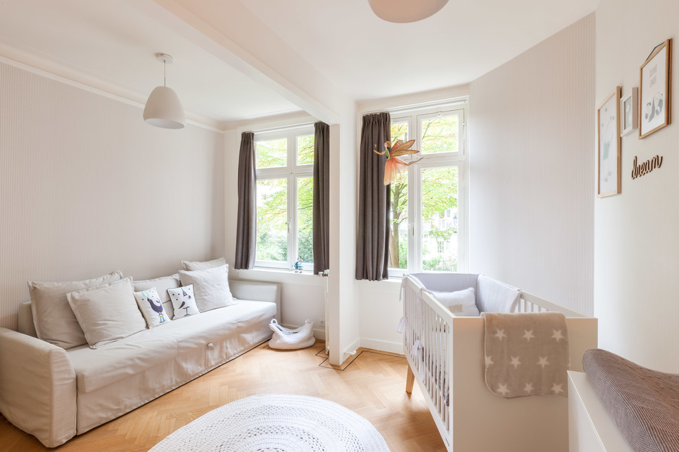 Photo of a scandinavian nursery for girls in Amsterdam with beige walls, light hardwood flooring and beige floors.