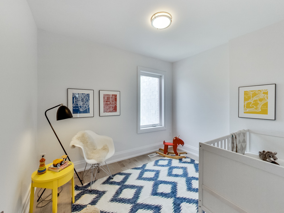 Exempel på ett mellanstort minimalistiskt babyrum, med vita väggar och ljust trägolv