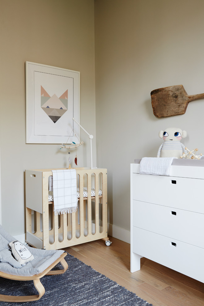 Cette photo montre une chambre de bébé neutre scandinave avec un mur beige et parquet clair.