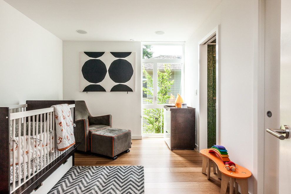 Ispirazione per una cameretta per neonati neutra contemporanea di medie dimensioni con pareti bianche e pavimento in legno massello medio