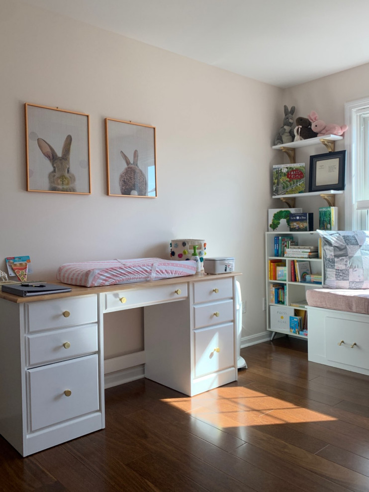 Ejemplo de habitación de bebé niña vintage de tamaño medio con paredes rosas, suelo de madera en tonos medios y suelo marrón