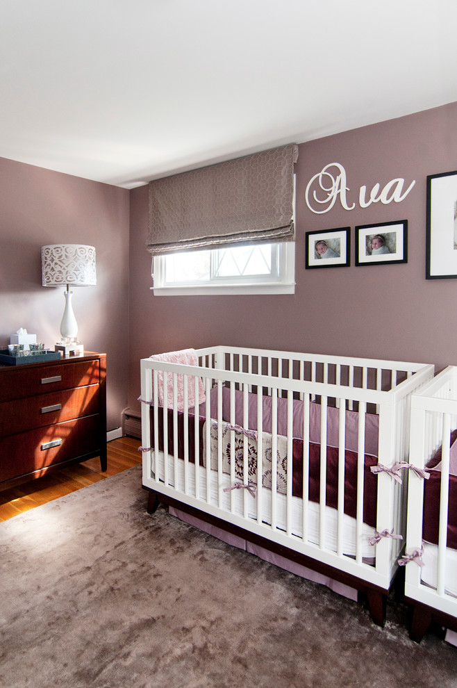 Medium sized modern nursery for girls in Other with purple walls and light hardwood flooring.
