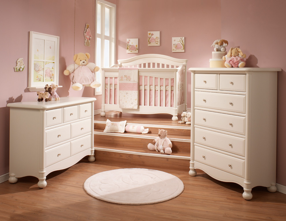 Idée de décoration pour une chambre de bébé fille design de taille moyenne avec un mur rose et parquet clair.