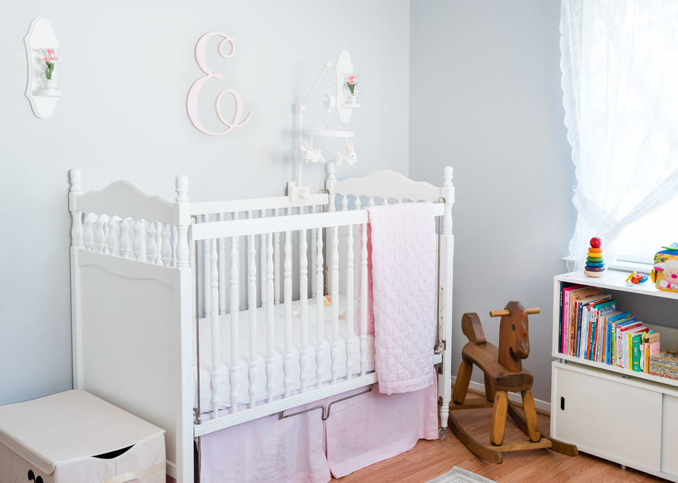 Modelo de habitación de bebé niña clásica con paredes grises y suelo de madera clara