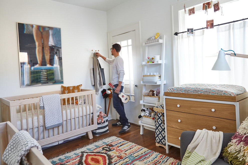 Diseño de habitación de bebé neutra clásica renovada con paredes blancas y suelo de madera en tonos medios