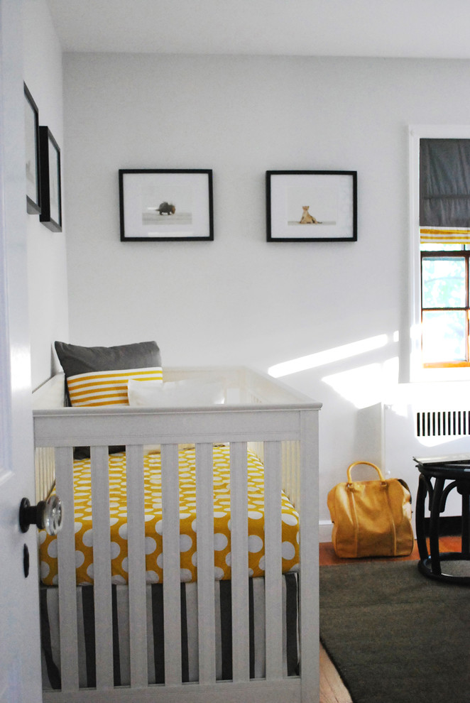 Small traditional nursery for boys in Boston with grey walls and light hardwood flooring.