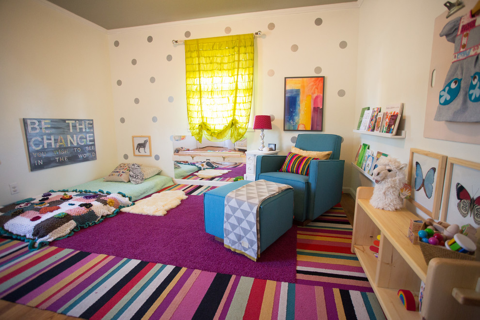 This is an example of a large bohemian nursery for girls in San Diego with beige walls and medium hardwood flooring.