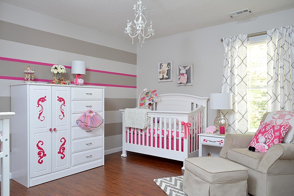 Diseño de habitación de bebé niña tradicional con paredes multicolor y suelo de madera en tonos medios