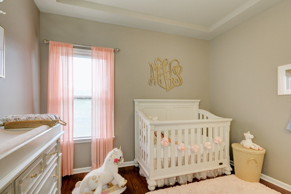 Idée de décoration pour une petite chambre de bébé fille style shabby chic avec un mur gris, un sol en bois brun et un sol marron.