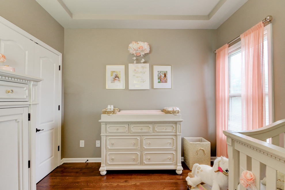 Photo of a small shabby-chic style nursery for girls in Nashville with grey walls, medium hardwood flooring and brown floors.
