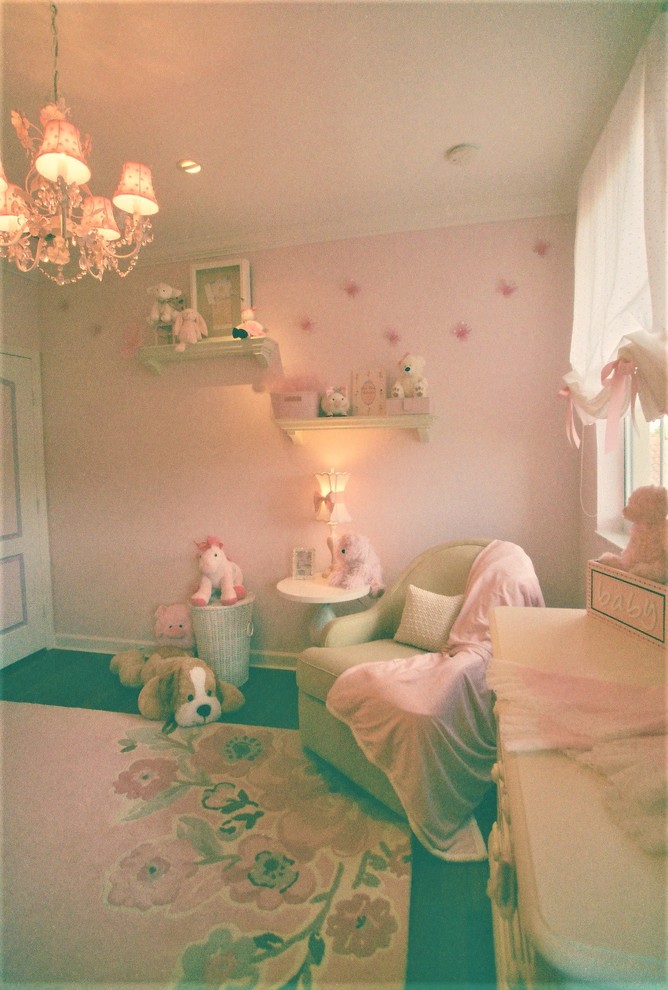 Cette photo montre une petite chambre de bébé fille romantique avec un mur rose et parquet foncé.