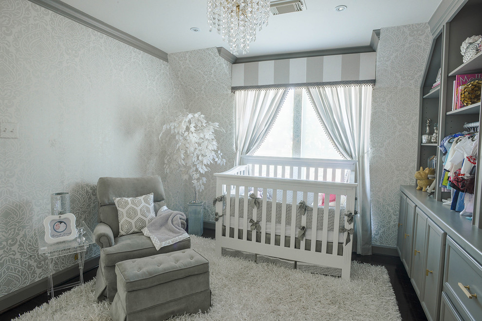 Modelo de habitación de bebé niña clásica renovada de tamaño medio con paredes blancas y suelo de madera oscura