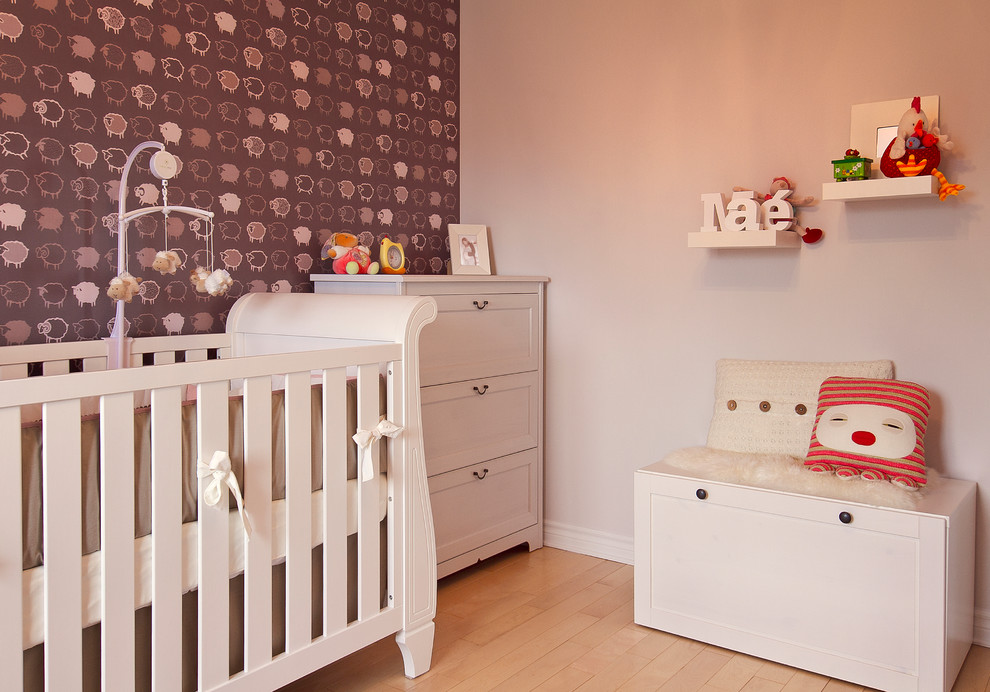 This is an example of a bohemian gender neutral nursery in Montreal with light hardwood flooring and multi-coloured walls.