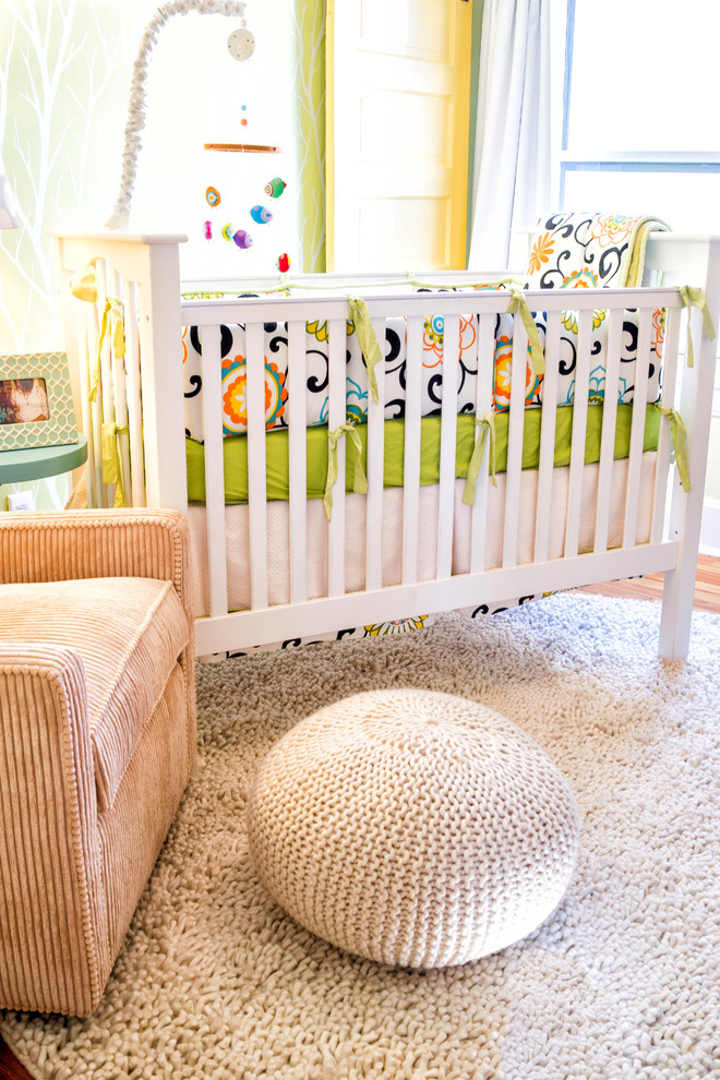 Cette photo montre une petite chambre de bébé neutre chic avec un mur jaune et un sol en bois brun.