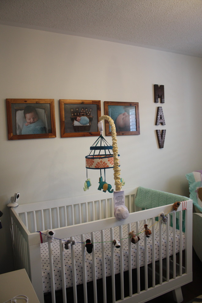 This is an example of a traditional nursery for boys in Toronto with white walls and dark hardwood flooring.
