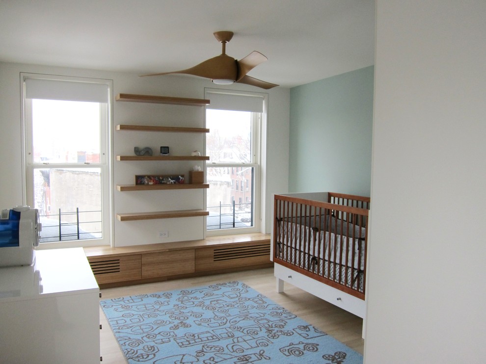 Diseño de habitación de bebé neutra actual de tamaño medio con paredes azules y suelo de madera clara