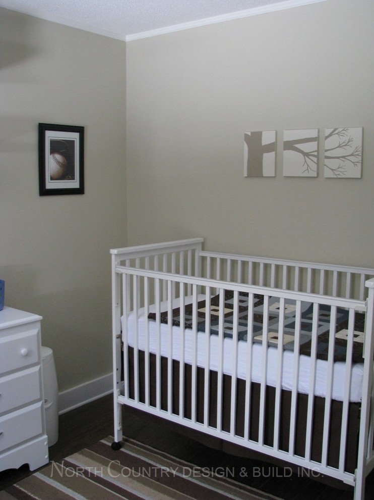 Ejemplo de habitación de bebé niño tradicional renovada pequeña con paredes beige y suelo de madera oscura
