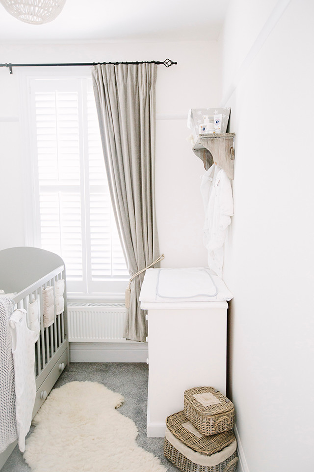 Foto på ett litet funkis könsneutralt babyrum, med grå väggar och heltäckningsmatta