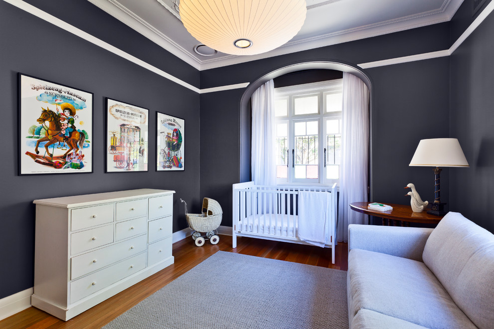 Idée de décoration pour une chambre de bébé neutre tradition de taille moyenne avec un mur noir et un sol en bois brun.