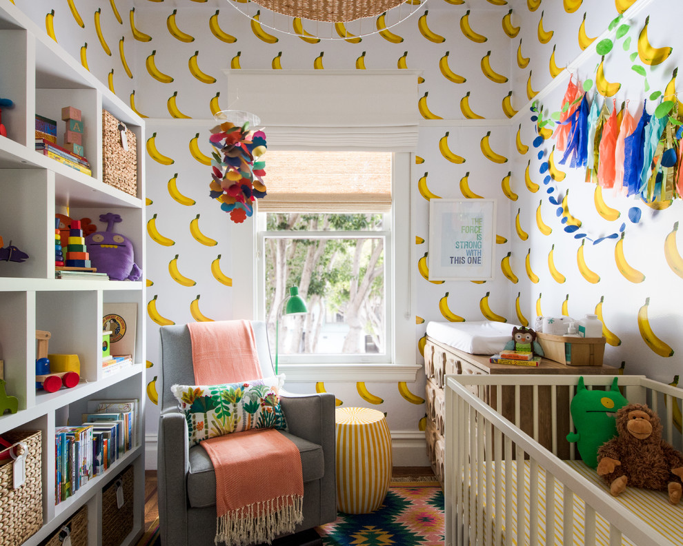 This is an example of a contemporary gender neutral nursery in San Francisco with white walls, medium hardwood flooring and brown floors.