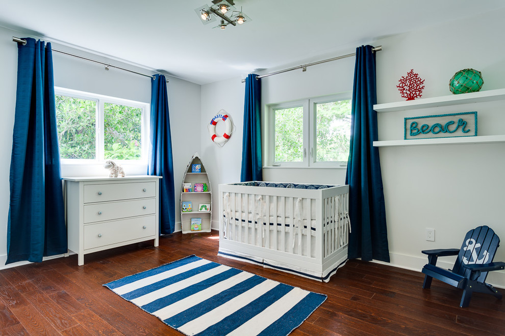 Пример оригинального дизайна: нейтральная комната для малыша в морском стиле с белыми стенами, темным паркетным полом и коричневым полом