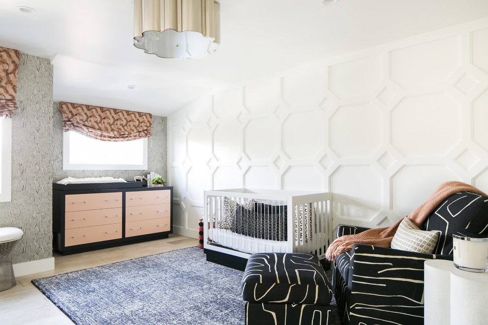 This is an example of a contemporary gender neutral nursery in Orange County with grey walls, light hardwood flooring, beige floors and a feature wall.