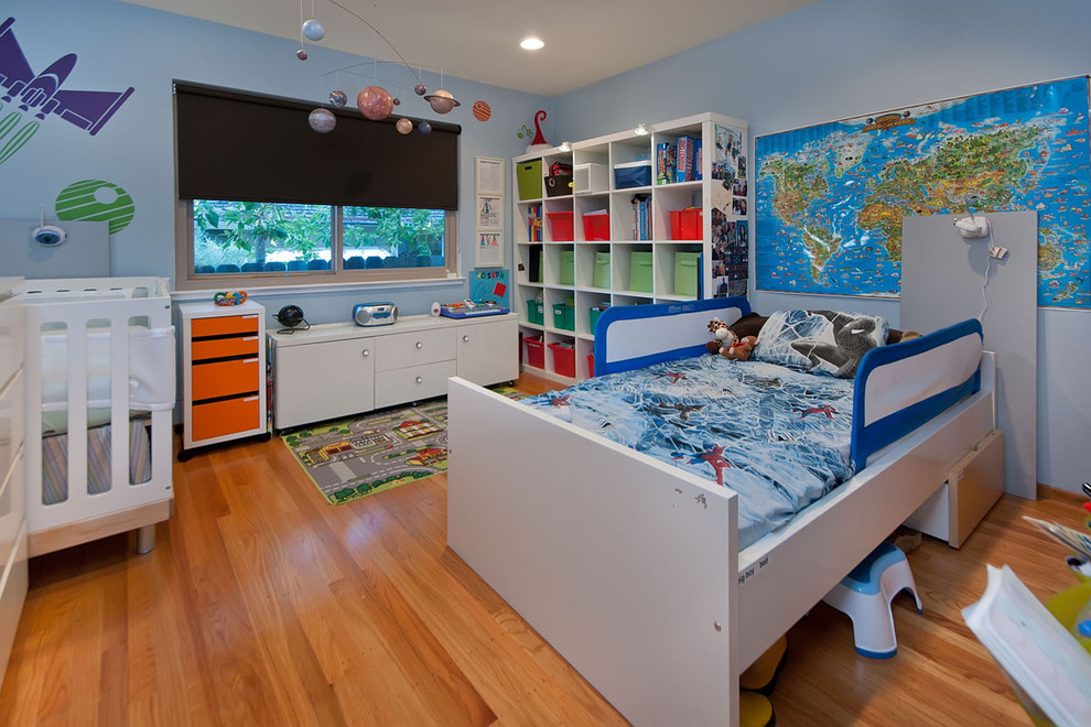 Aménagement d'une grande chambre de bébé garçon contemporaine avec un mur bleu et un sol en bois brun.