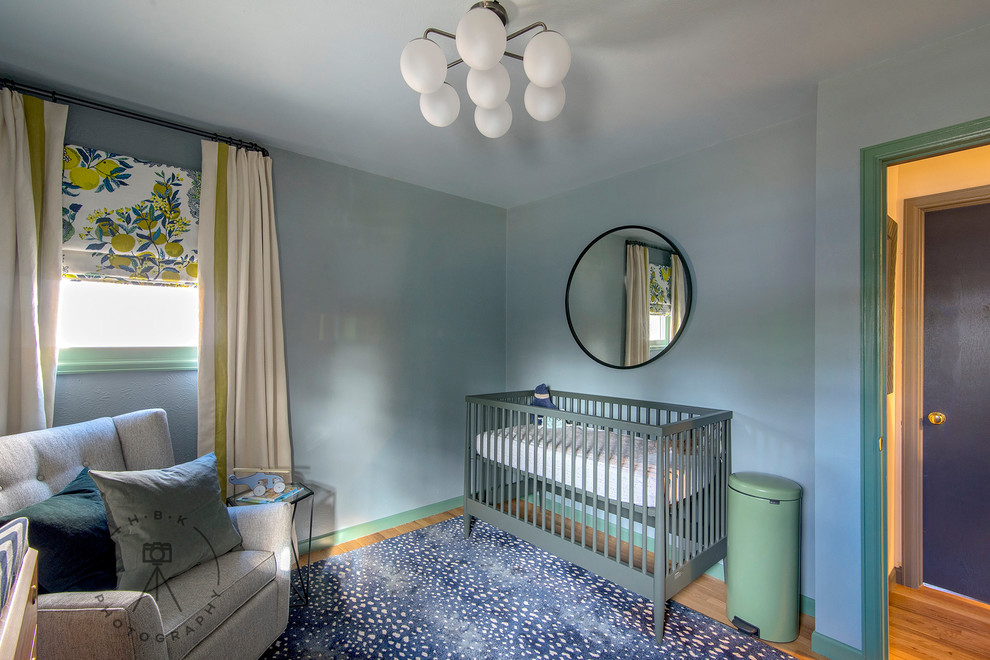 This is an example of a small world-inspired gender neutral nursery with blue walls, light hardwood flooring and yellow floors.