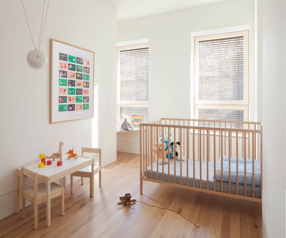 Nursery - scandinavian gender-neutral medium tone wood floor and brown floor nursery idea in New York with white walls