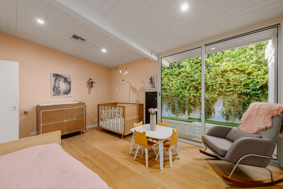 Modelo de habitación de bebé niña retro grande con paredes rosas y suelo de madera clara