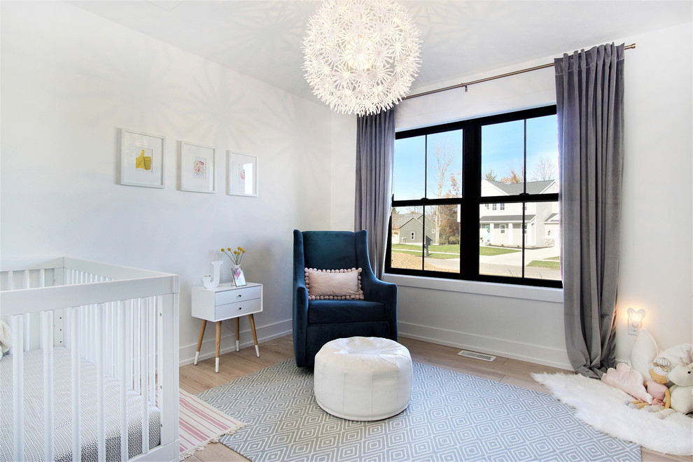 Immagine di una cameretta per neonata nordica di medie dimensioni con pareti bianche, parquet chiaro e pavimento beige