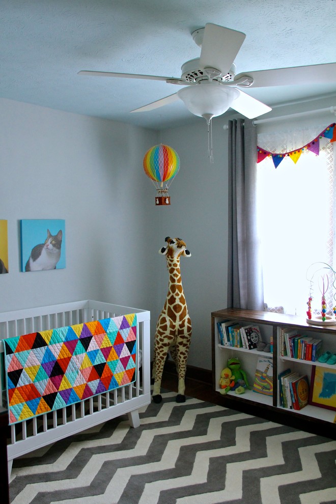 Imagen de habitación de bebé neutra tradicional de tamaño medio con paredes grises y suelo de madera oscura
