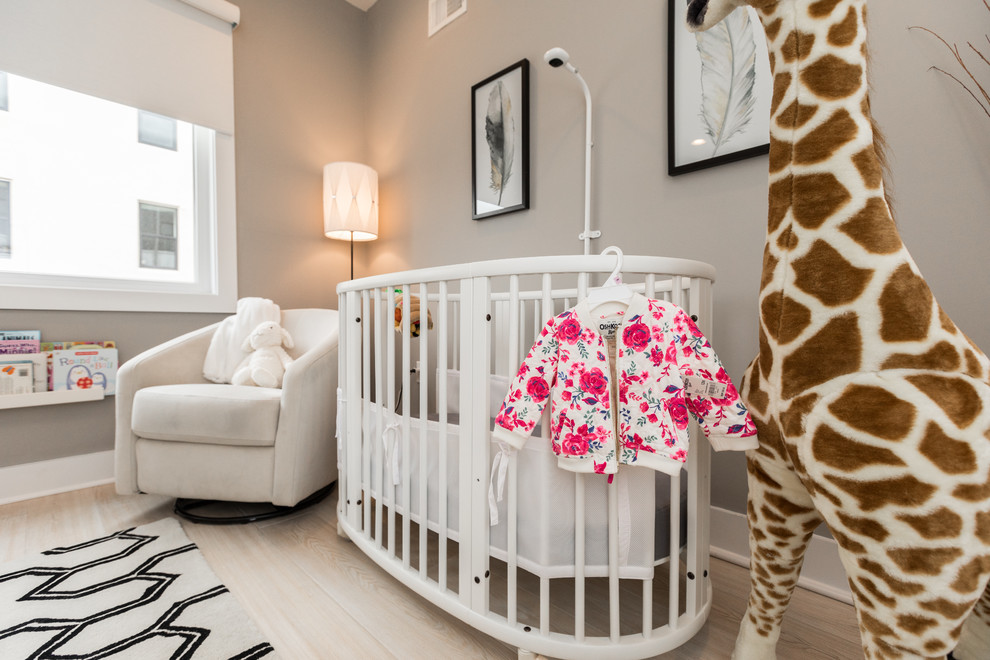 Esempio di una cameretta per neonata minimalista di medie dimensioni con pareti grigie, parquet chiaro e pavimento beige