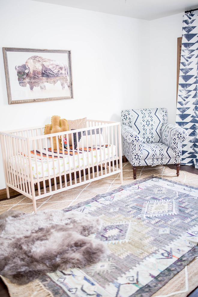 Modelo de habitación de bebé niño de estilo americano de tamaño medio con paredes blancas, suelo de madera oscura y suelo marrón