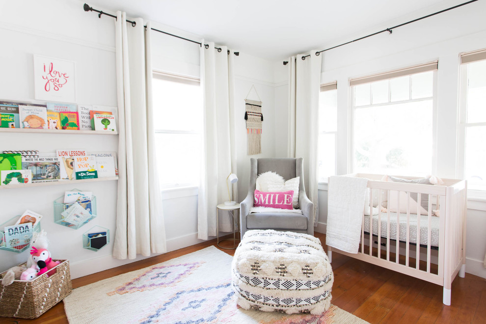 Ispirazione per una cameretta per neonata tradizionale con pareti bianche, pavimento in legno massello medio e pavimento marrone