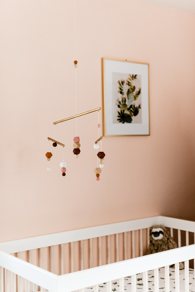 Idée de décoration pour une petite chambre de bébé fille bohème avec un mur rose et sol en stratifié.