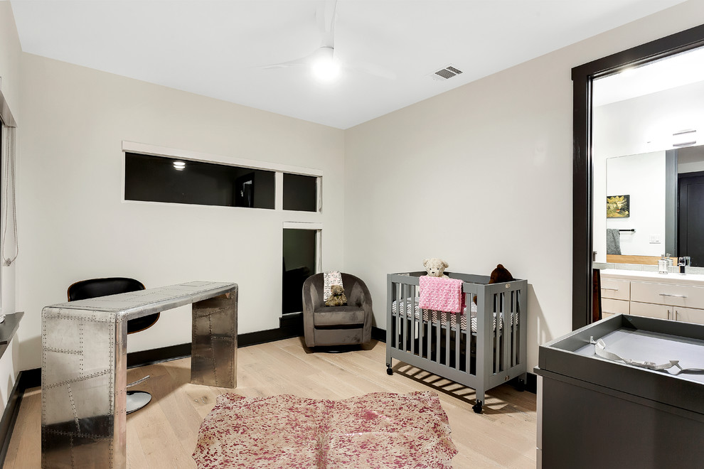 Immagine di una cameretta per neonata chic di medie dimensioni con pareti bianche e parquet chiaro