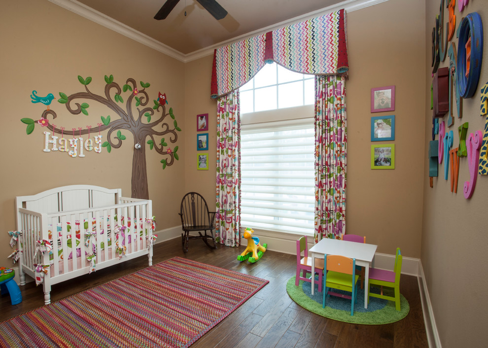 Modelo de habitación de bebé niña clásica de tamaño medio con suelo de madera en tonos medios, paredes beige y suelo marrón
