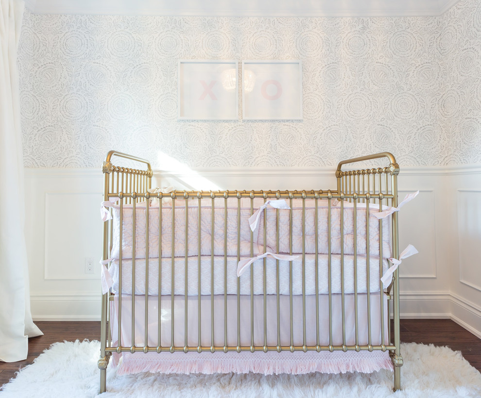 Imagen de habitación de bebé niña clásica renovada grande con paredes blancas, suelo de madera oscura y suelo marrón