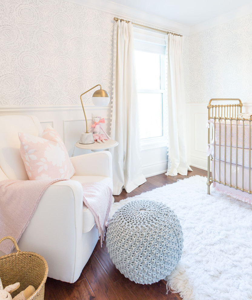Diseño de habitación de bebé niña clásica renovada grande con paredes blancas, suelo de madera oscura y suelo marrón
