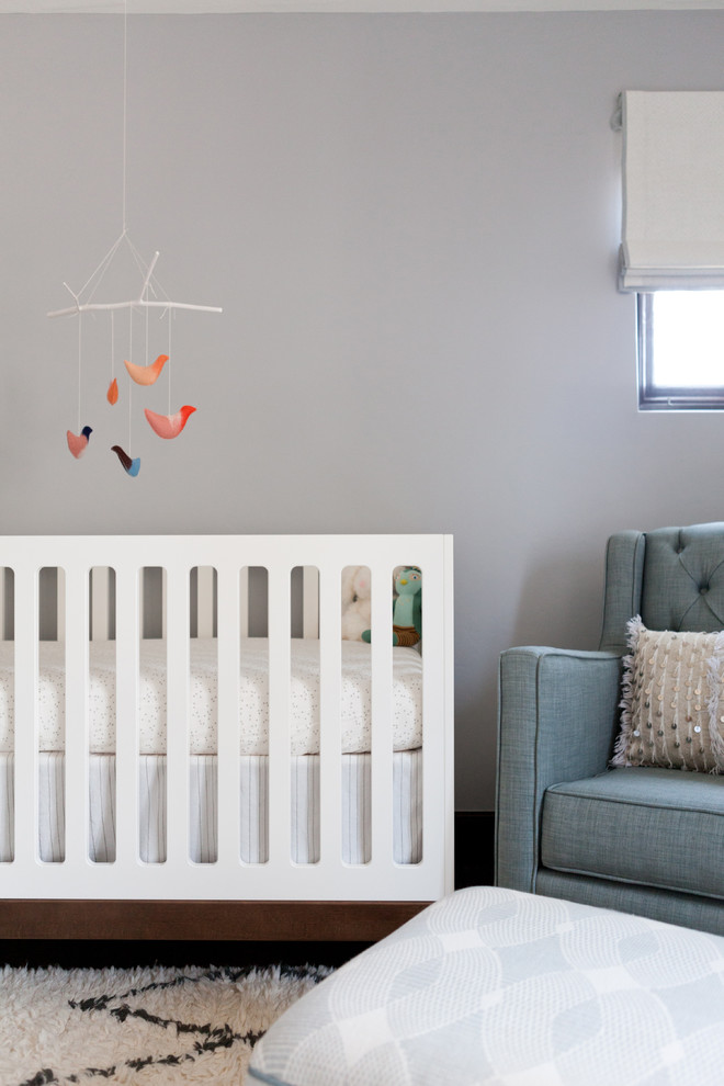 Diseño de habitación de bebé neutra clásica renovada de tamaño medio con paredes grises, suelo de madera en tonos medios y suelo marrón