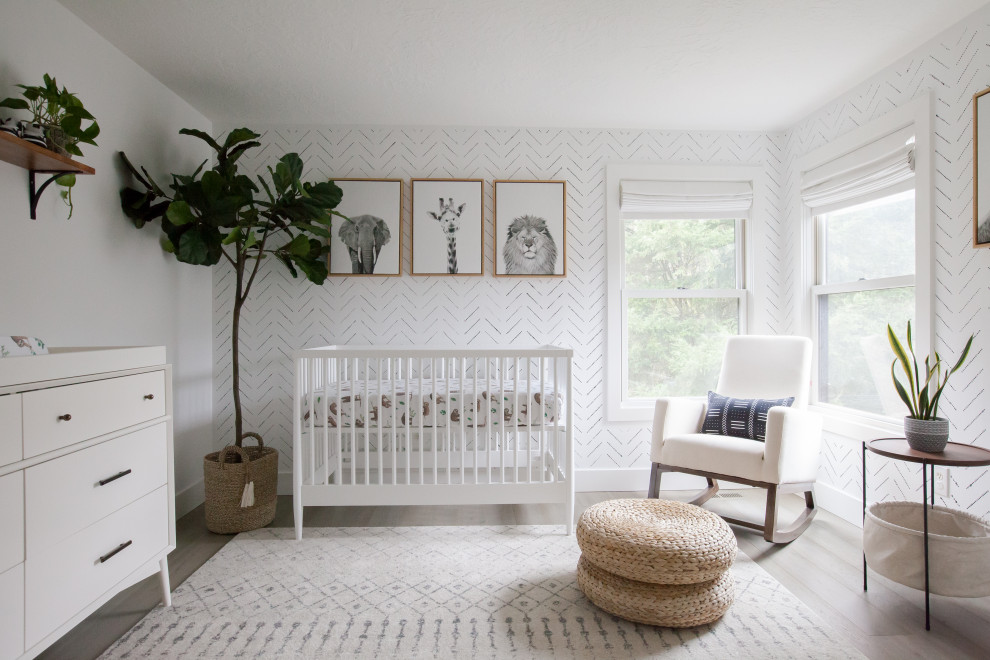Modelo de habitación de bebé neutra nórdica con paredes blancas, suelo de madera en tonos medios, suelo marrón y papel pintado