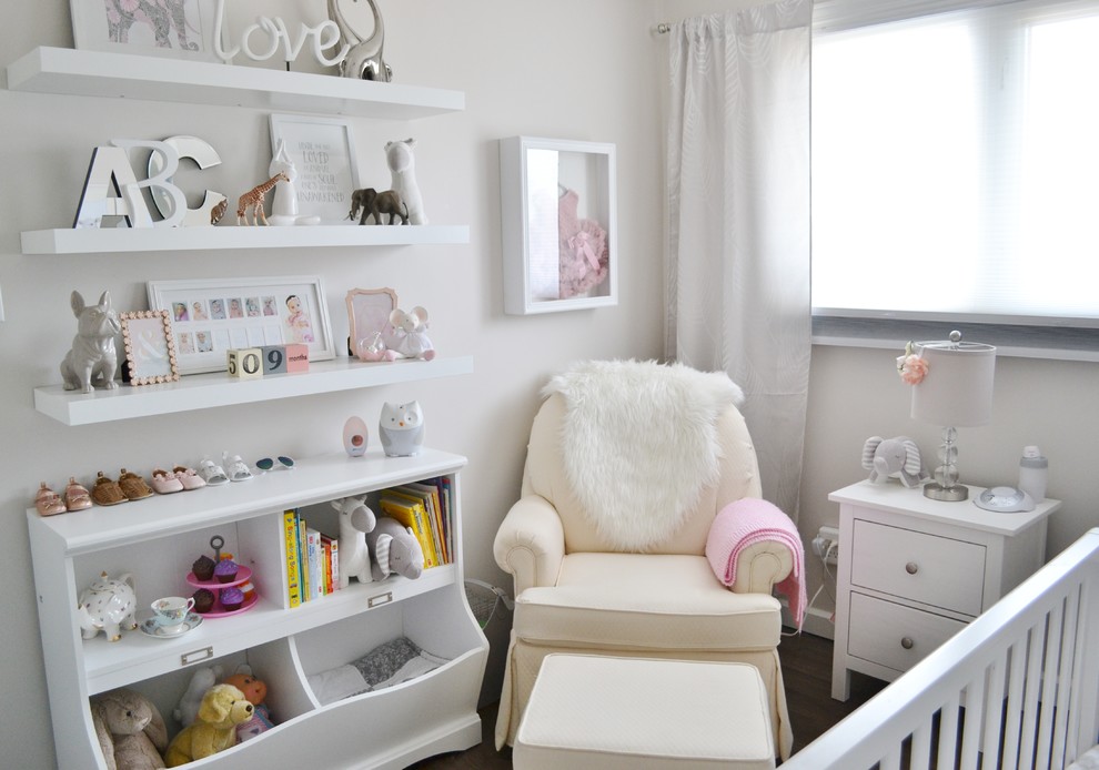 Imagen de habitación de bebé niña clásica pequeña con paredes beige y suelo laminado